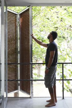 a man standing in front of an open door with his hand on the glass railing