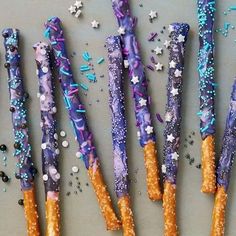 five purple and blue decorated sticks with sprinkles on them sitting on a table