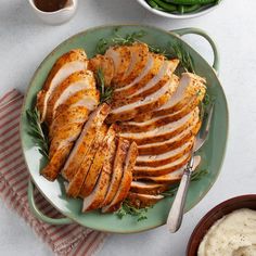 sliced turkey on a plate with green beans and mashed potatoes