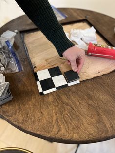 a person is painting some black and white tiles on a table with a red brush