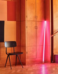 a chair sitting on top of a hard wood floor next to a tall wooden cabinet