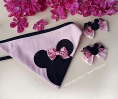 pink and black minnie mouse purse with matching hair clips on white surface next to purple flowers