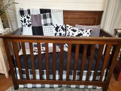 a wooden crib with black and white pillows on it