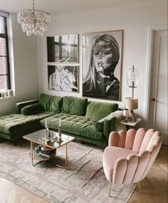 a living room with green couches and pictures on the wall above them, as well as a chandelier