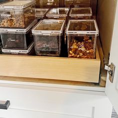 several plastic containers filled with nuts and other food items on a shelf in a kitchen