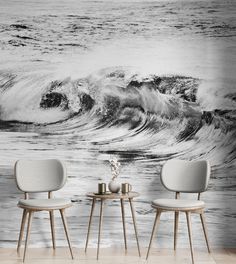 two chairs sitting next to each other in front of a wall with waves on it