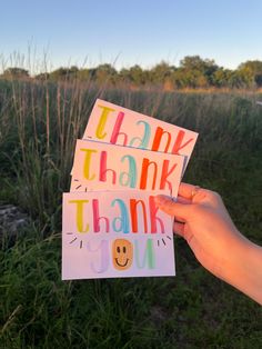 someone is holding up some thank cards in the grass with words on them that read thank you