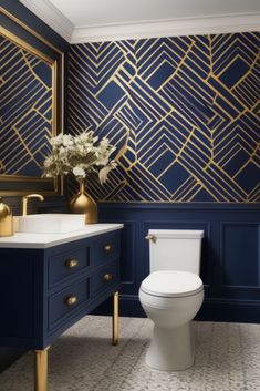 a white toilet sitting next to a sink in a bathroom under a golden framed mirror