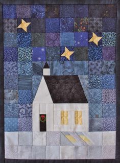 a quilted wall hanging with a house and stars in the sky on top of it