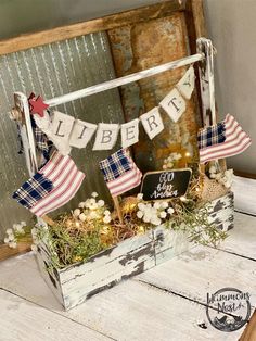 a wooden box filled with flags and flowers on top of a table next to a sign that says liberty