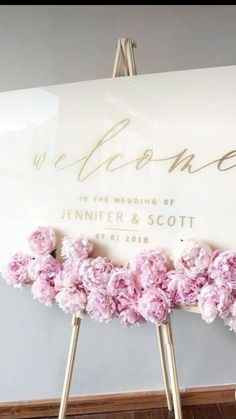 a sign with pink flowers on it in front of a wall