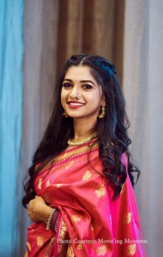 a woman in a red and gold sari smiles at the camera while holding a teddy bear