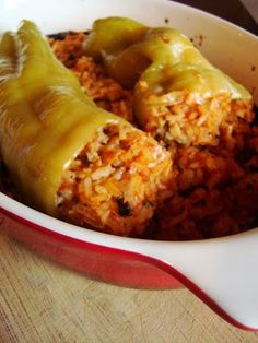 two burritos in a red and white dish on a wooden table with rice