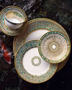 three plates and two bowls sitting on top of each other next to a gold fish