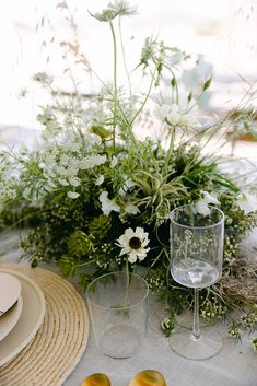 the table is set with plates, glasses and flowers