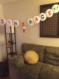 a green couch sitting in a living room next to a wall with letters on it