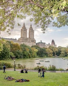 people are sitting on the grass near a lake in central park, new york city