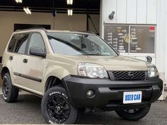 a beige suv parked in front of a building