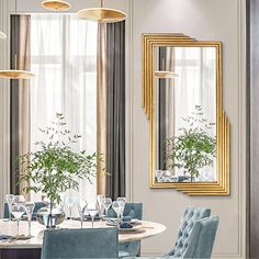 a dining room with blue chairs and gold framed mirrors