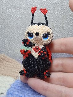 a hand holding a tiny beaded cat ornament