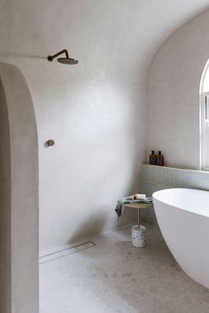 a large white bath tub sitting under a window next to a sink in a bathroom