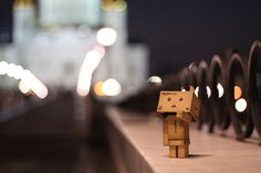 a wooden toy standing on top of a bridge next to a street filled with traffic lights