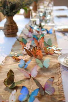 the table is set with many colorful butterflies on top of burlocked cloth