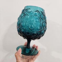 a hand holding up a blue glass vase