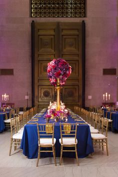 the tables are set up with blue linens and gold chairs for an elegant reception