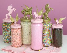 there are many different types of candy in the jars with unicorn figurines on top