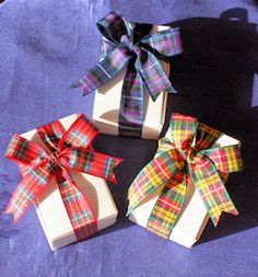 three wrapped gift boxes sitting on top of a purple cloth covered table next to each other