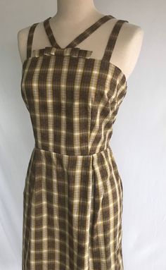 Adorable 1950's reproduction sundress made from actual 1950's novelty woven plaid! Plaid has kind of an optical illusion effect with how it was woven and in the middle of each square is a tic-tac-toe "OXO"! Bodice is fitted with double straps that meet at the center front and center back. There's a box bow at center front neck. Skirt is straight with a nice slit at the back for ease of movement. Dress zips up the side with a vintage cotton tape and metal teeth white zipper. Bodice is fully lined in a buttercream yellow cotton.  Dress is clean and in great condition! Measurements: would best fit a modern size M Bust= 37 1/2" Waist= 32" Hip= 47 1/2" Strap length= 13" Body length from top fold of strap down to hem edge= 44" Pattern Dress Design, Yellow Cotton Dress, Pin Up Dresses, Dress Pin, Rockabilly Dress, White Teeth, Wiggle Dress, Straight Skirt, Vintage Cotton