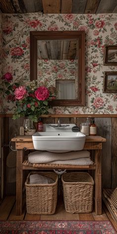 a white sink sitting under a mirror next to a wooden table with baskets on it