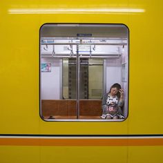 a woman is sitting in the window of a train with her cat on her lap