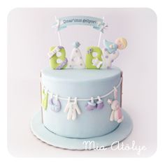 a baby's first birthday cake is decorated with clothes and bunting on the top