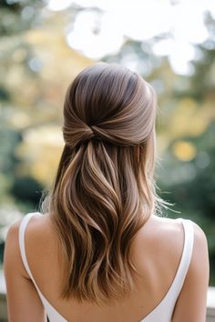 a woman with long hair wearing a white dress and braided in half - up