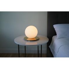 a white lamp sitting on top of a table next to a bed