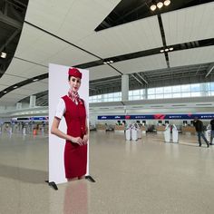 a woman in an airplane attendant's uniform is standing next to a large sign