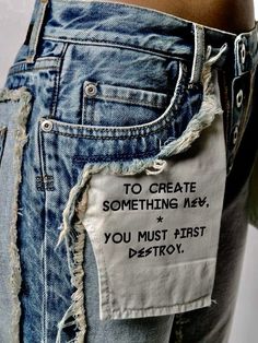 someone has ripped up their jeans with some writing on them and the words to create something new, you must first destroy