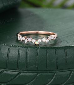 a rose gold ring with opal and diamonds on top of a green car tire