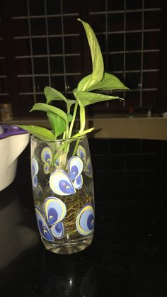 a plant in a glass vase with blue and white designs on the bottom, sitting on a table