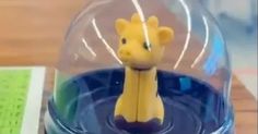 a toy giraffe is under a glass dome