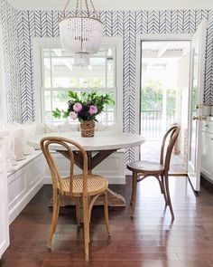 a dining room table and chairs in front of a window with blue chevron wallpaper