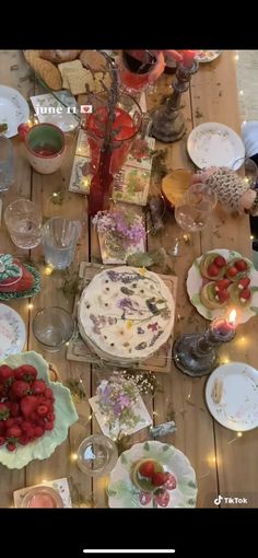 a wooden table topped with plates and bowls filled with cake next to candles on top of it