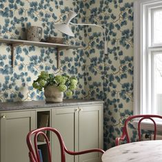 a table and chairs in a room with floral wallpaper on the walls behind them