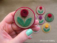 a hand holding a piece of felt with flowers on it and several other items in the background