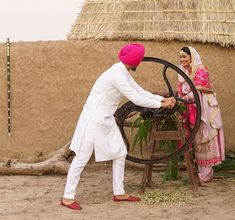 a man and woman standing next to each other near a wheel