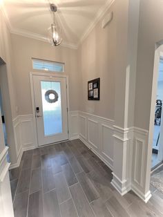 an empty hallway with white walls and wood flooring is pictured in this image from the front door