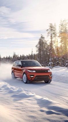 a red range rover driving through the snow