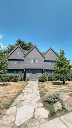 a large gray house sitting on top of a lush green field